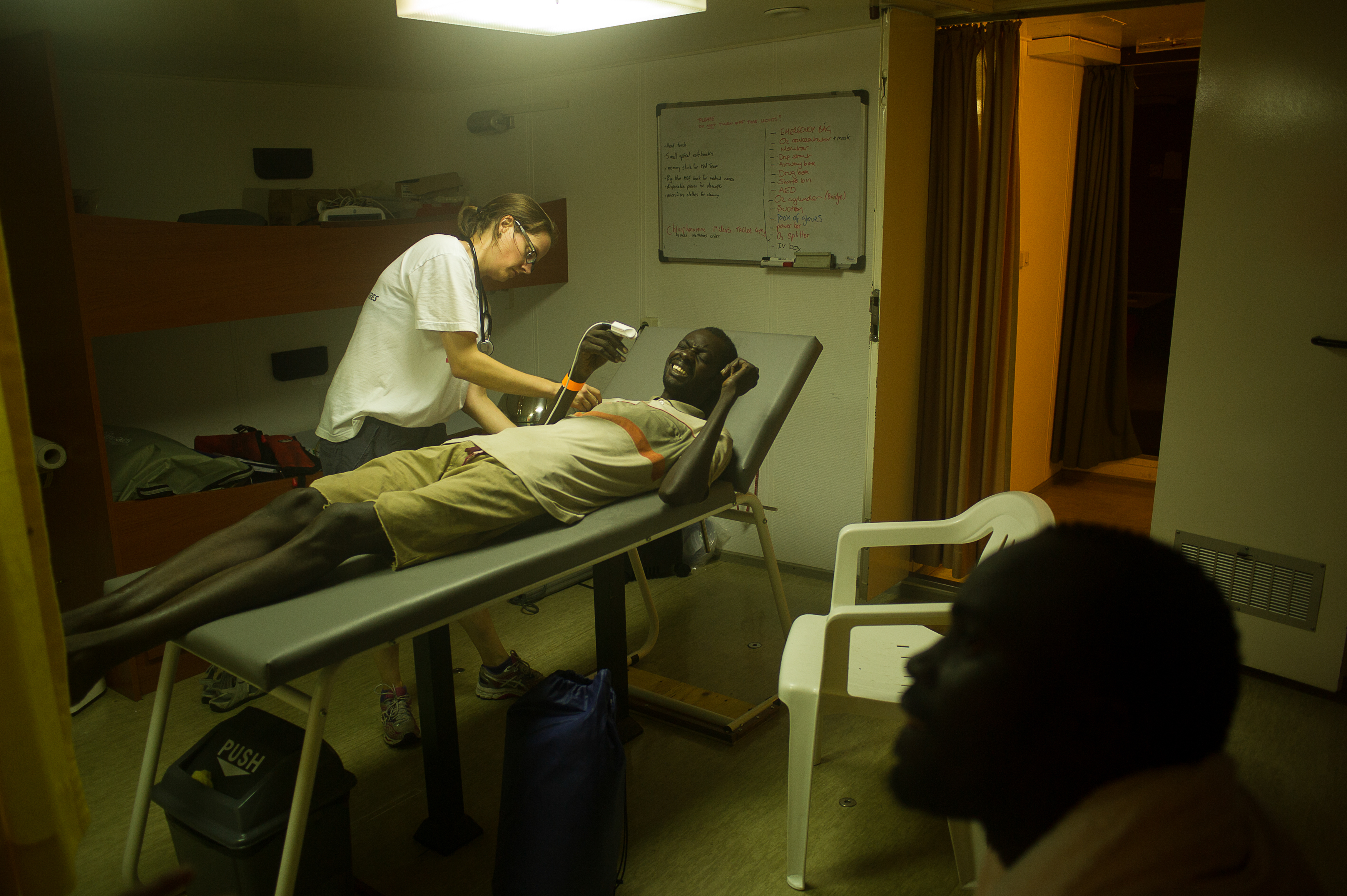 Dr. Sarah Gilles from the humanitarian organization Doctors Without Borders examining a migrant rescued at the mediterranean. The man arrived at the boat complaining of strong abdominal and chest pain and was taken to the clinic for examination.